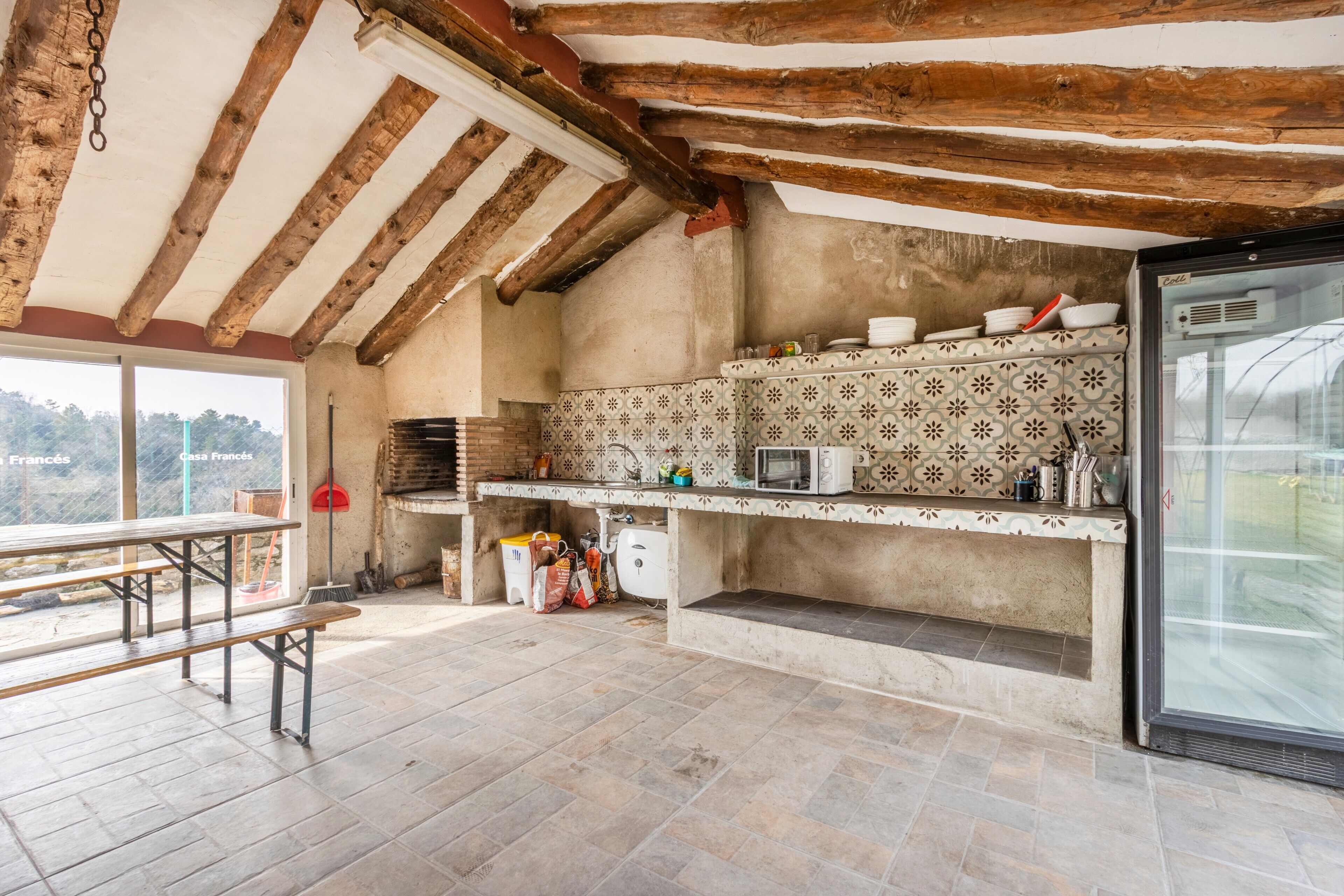 Cocina rústica con vigas de madera a la vista, salpicadero de azulejos y un amplio ventanal con vistas panorámicas.
