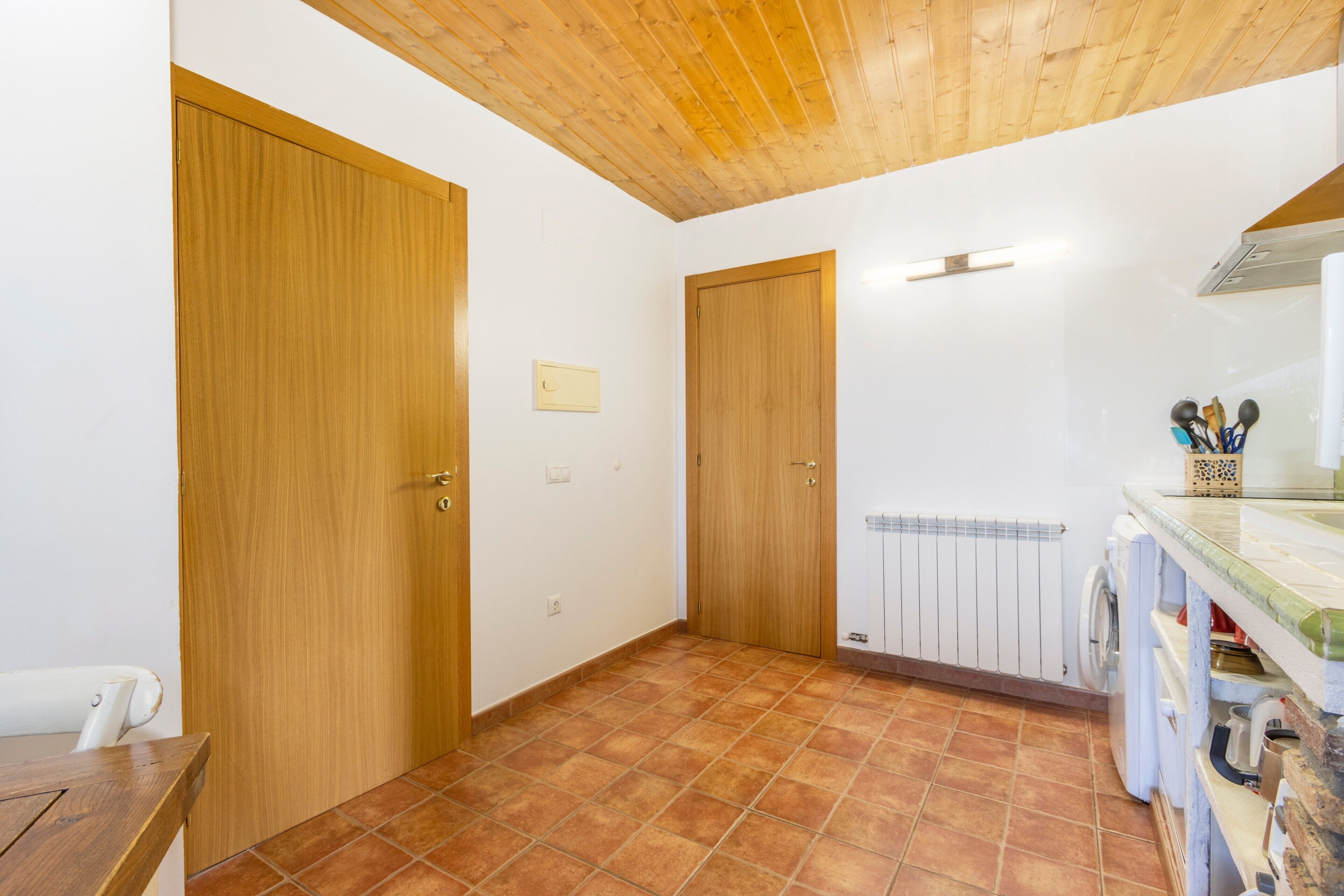 Een kamer met houten deuren, betegelde vloer, een radiator en een wasmachine.