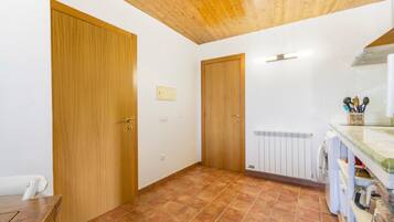 Een kamer met houten deuren, betegelde vloer, een radiator en een wasmachine.