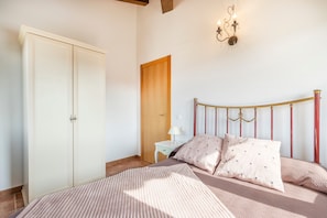 Quarto com cama, guarda-roupa, mesa de cabeceira e lustre.