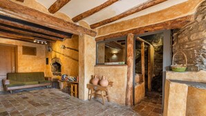 A rustic interior with exposed wooden beams, a stone fireplace, and a stone floor. - Apartment 'La Coma' with Mountain Views, Private Pool and Wi-Fi (Graus)