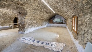 An interior with stone walls, a tiled floor with a map, a bench, and a window. - Apartment 'La Coma' with Mountain Views, Private Pool and Wi-Fi (Graus)