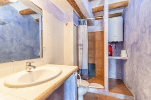 Ein Badezimmer mit Waschbecken, Toilette, Dusche und Warmwasserbereiter.