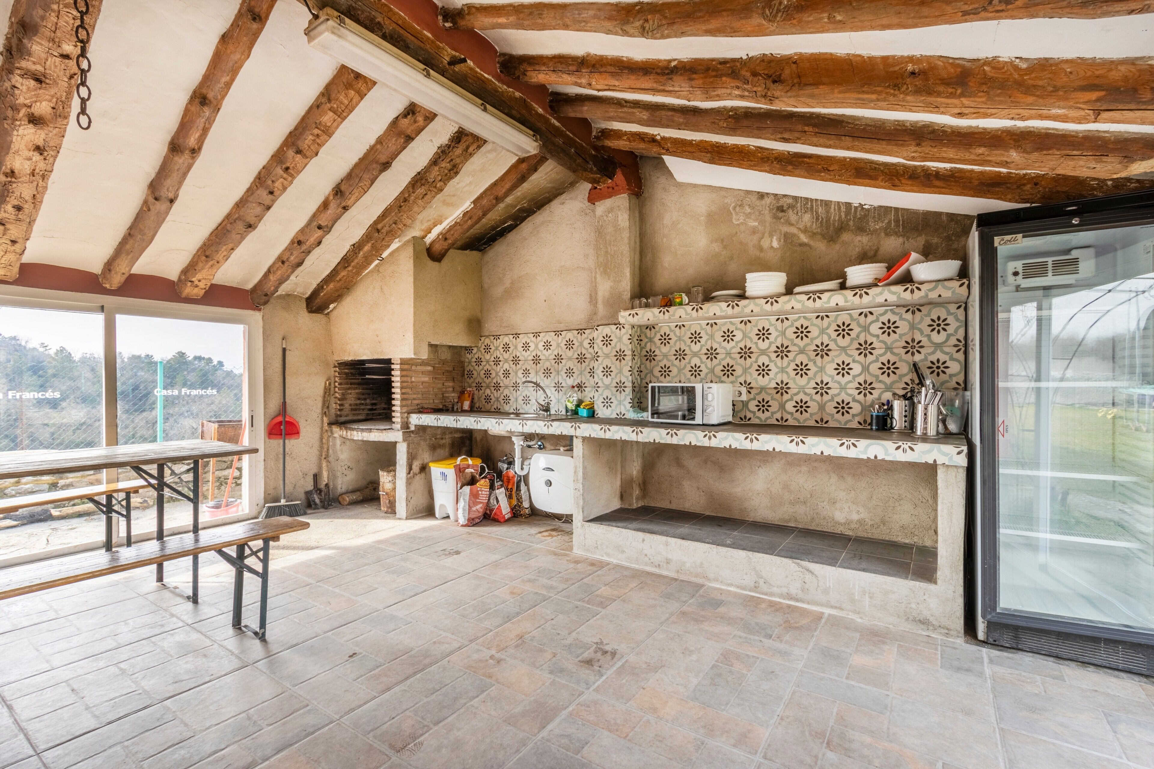 Una cocina rústica con vigas de madera a la vista, salpicadero de azulejos y un amplio ventanal con vistas panorámicas.