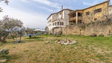 A stone wall, a grassy area, and a building with a tiled roof.
