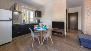 A modern kitchen with a dining area, a flat-screen TV, and a sofa. - Apartment 'Citronela' with Private Terrace and Air Conditioning (Nijar)
