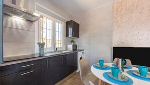 A modern kitchen with a built-in oven, microwave, and washing machine. There is a dining table with blue placemats and cups. - Apartment 'Citronela' with Private Terrace and Air Conditioning (Nijar)