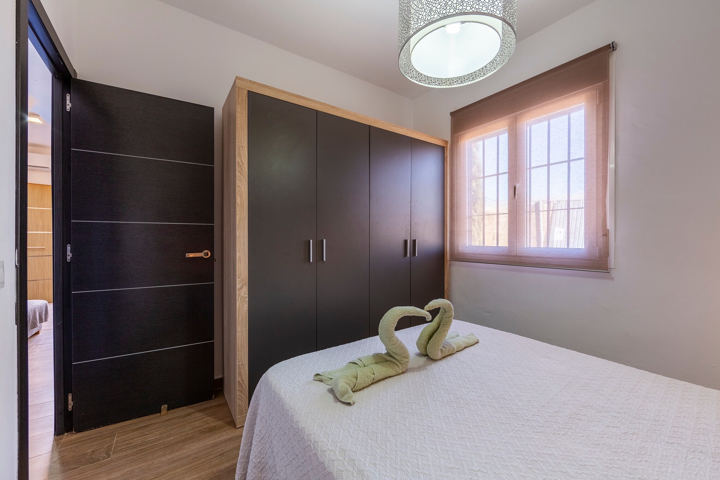 A bedroom with a bed, a wardrobe, and a window.