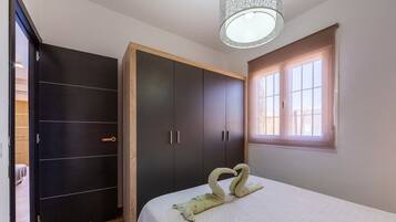 A bedroom with a bed, a wardrobe, and a window.