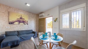 A living area with a sofa, a dining table with chairs, a painting of the Eiffel Tower, and a window with a view. - Apartment 'Citronela' with Private Terrace and Air Conditioning (Nijar)