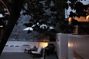 An outdoor seating area with a stone wall, a large planter, and a table with chairs.