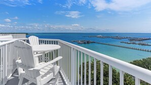 Een balkon met witte stoelen en een tafel, met uitzicht op een jachthaven met steigers en boten.
