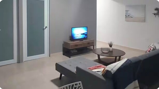 Un soggiorno con divano, tavolino, televisore su mobile e una porta.