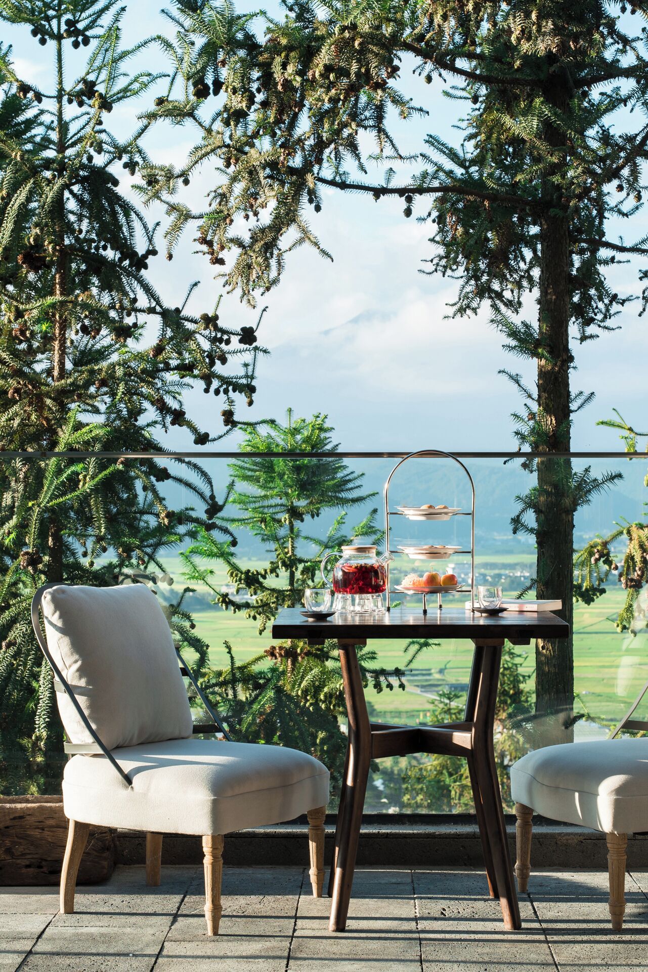 A terrace with a table set for tea, overlooking a scenic landscape.