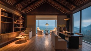 Una habitación amplia con techo alto, vigas de madera, un gran ventanal con vistas a la ciudad y muebles modernos.