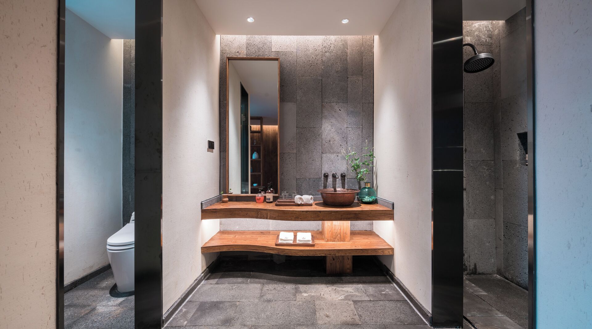 Un baño moderno con tocador de madera, un espejo grande y zona de ducha.