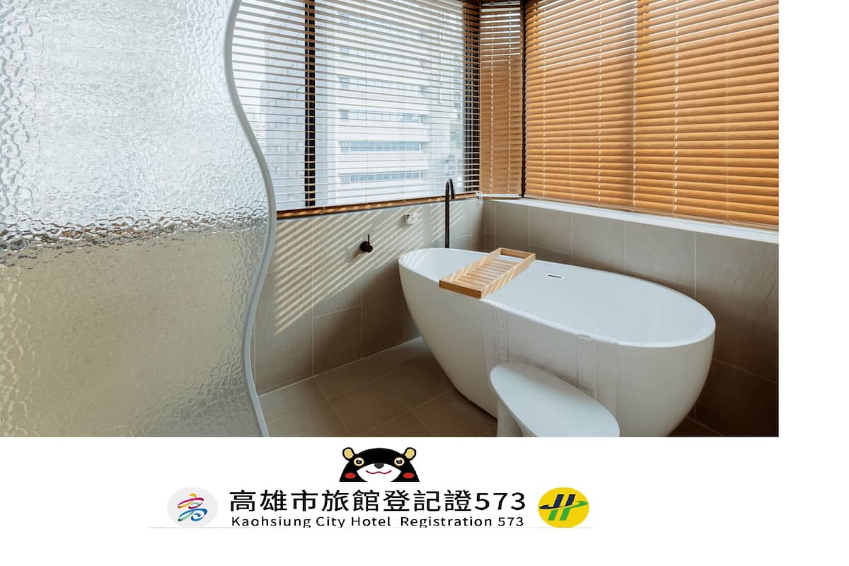 A modern bathroom with a freestanding bathtub, wooden blinds, and a towel rack.