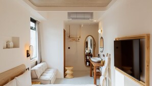 Un dormitorio moderno con una cama grande, cabecera de madera, mesita de noche, espejo y televisor montado en la pared.