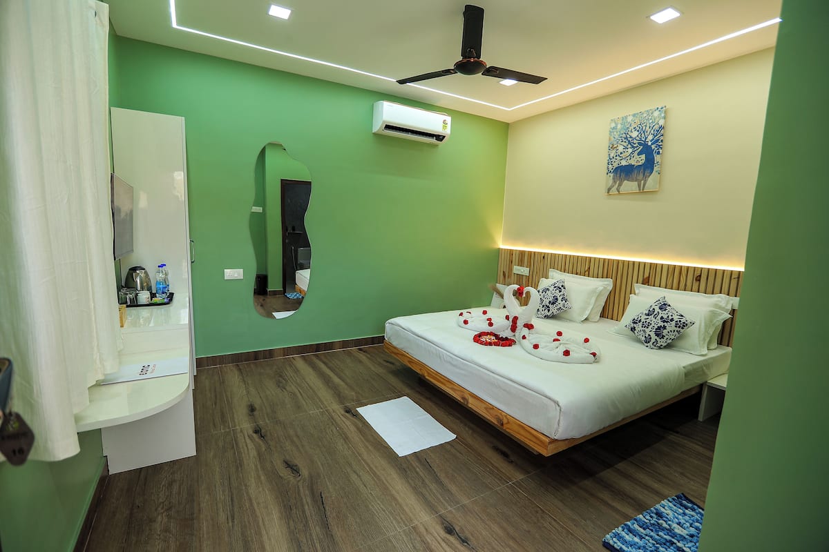 Ein modernes Hotelzimmer mit Bett, Deckenventilator, Klimaanlage, Spiegel und einem Bild an der Wand.