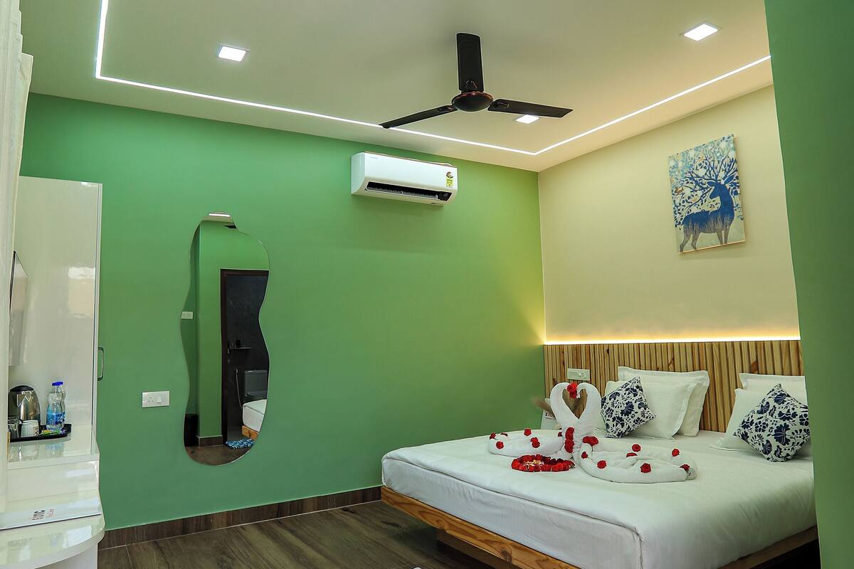 Ein modernes Hotelzimmer mit Bett, Deckenventilator, Spiegel und einem Bild an der Wand.