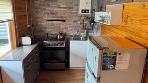 A compact kitchen with a gas stove, a small refrigerator, and a sink. - Mateo Puyuhuapi Cabin (Puyuhuapi)