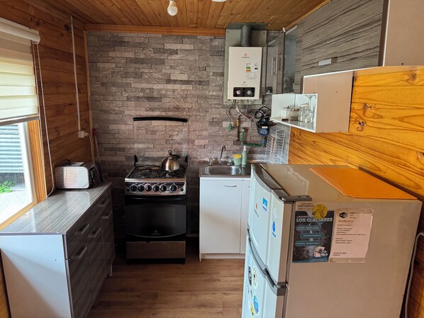 A compact kitchen with a gas stove, a small refrigerator, and a sink.