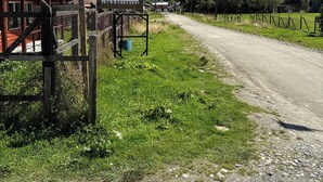 A rural road with a wooden sign for 'MATEO CABANAS' and a mountain backdrop. - Mateo Puyuhuapi Cabin (Puyuhuapi)