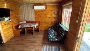 A wooden interior with a bed, sofa, and a small table. - Mateo Puyuhuapi Cabin (Puyuhuapi)