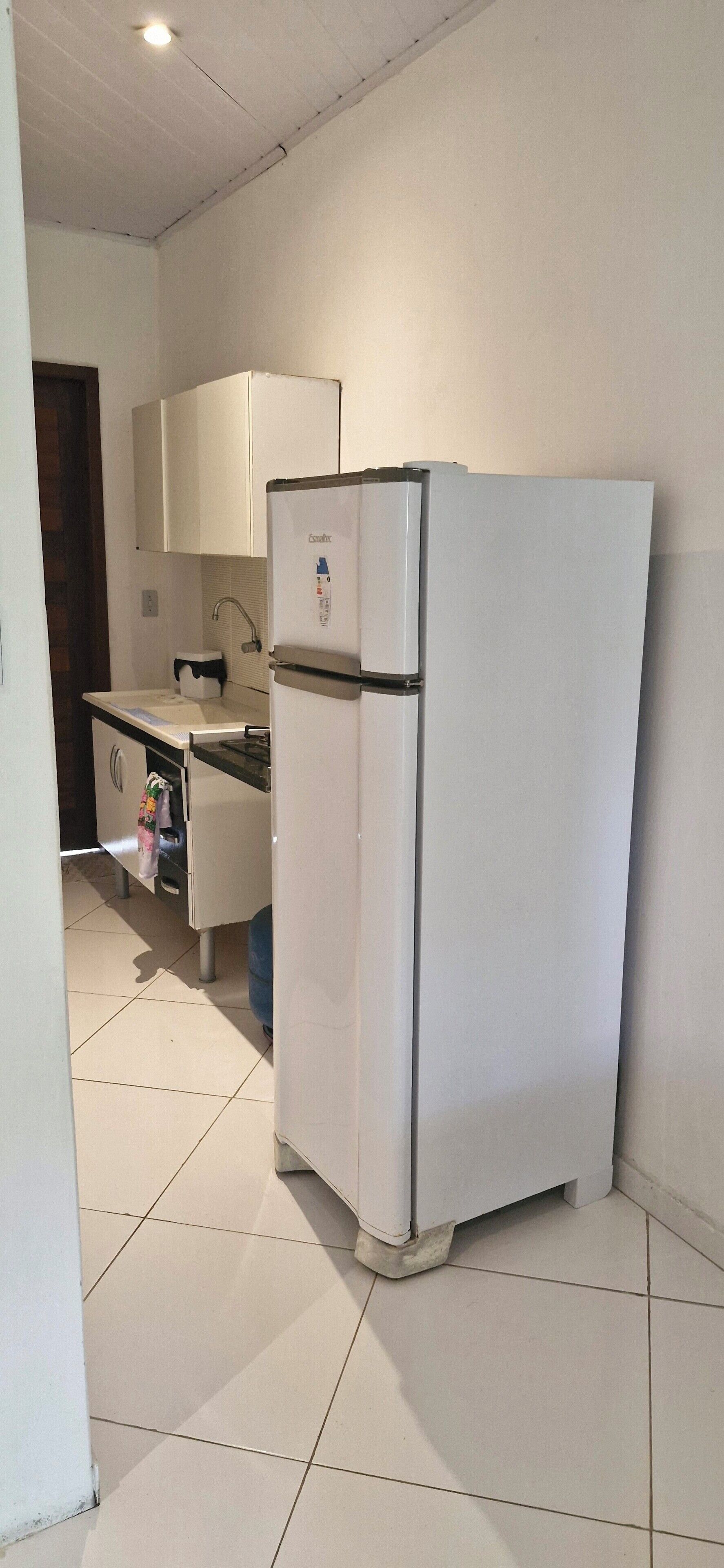 A compact kitchen with a white refrigerator, a sink, and cabinets.