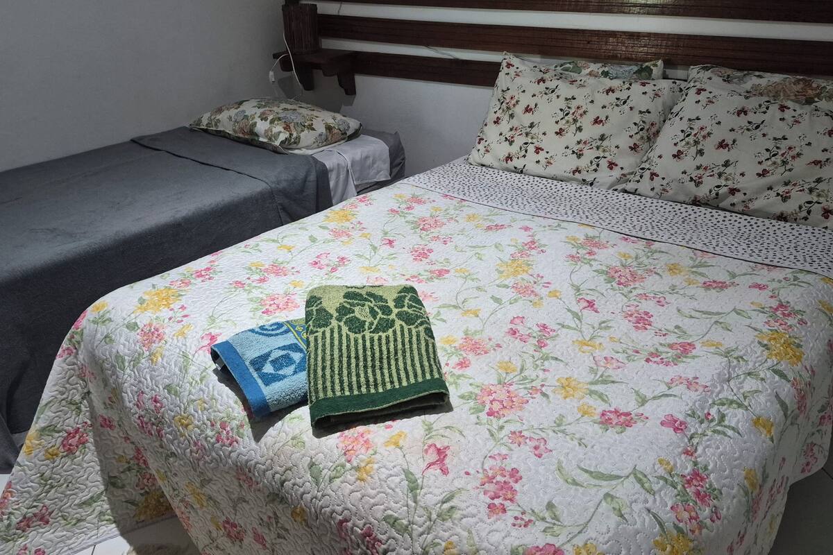 A bedroom with a single bed and a smaller bed, both with floral bedding.