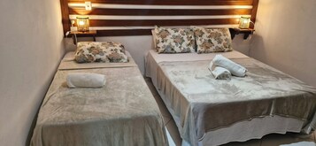Et hotelværelse med to senge, hver med pude med blomstermønster og et pænt foldet håndklæde. Der er sengeborde i træ med lamper.