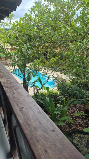 A view of a swimming pool surrounded by lush greenery and a wooden deck. - Cores de Boipeba  (Cairu)
