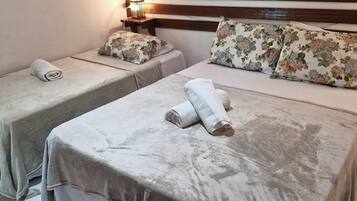 Two twin beds with floral bedding and towels, a bedside table with a lamp, and a wooden headboard.