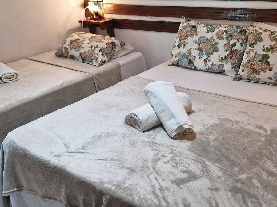 Two twin beds with floral bedding and towels, a bedside table with a lamp, and a wooden headboard.