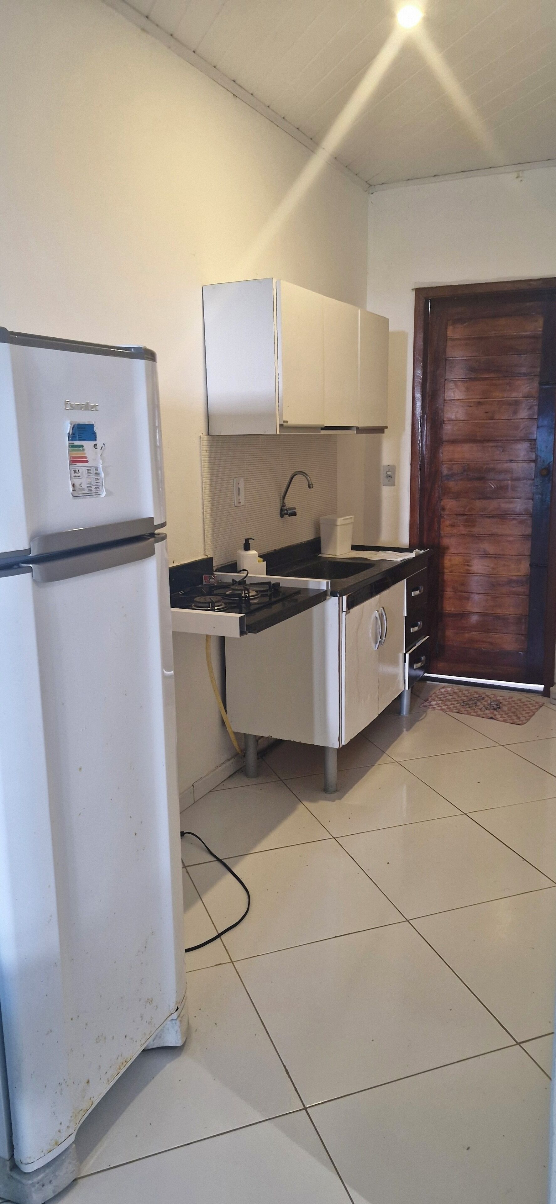 Una cocina compacta con refrigerador, lavamanos y armarios.