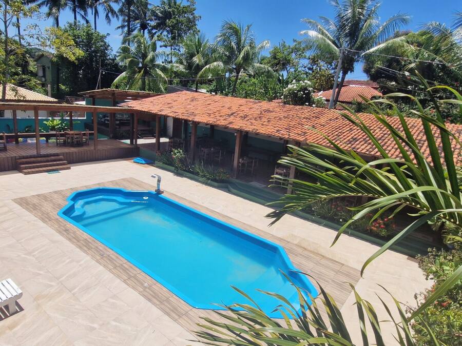 A swimming pool with lounge chairs, a covered patio, and surrounding tropical vegetation.