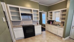 A kitchen with white cabinets, a black stove, and a window with blinds. - Charming 2 BR retreat in Shreveport, minutes from Casinos, airport & attractions (Shreveport)