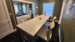 A dining area with a white table and chairs, a window with blinds, and a door leading to another room. - Charming 2 BR retreat in Shreveport, minutes from Casinos, airport & attractions (Shreveport)