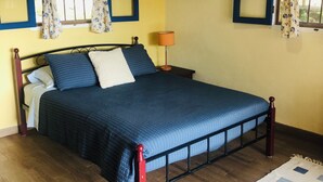 Une chambre à coucher avec un lit, des rideaux, un climatiseur et une lampe.