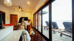 A room with a large window overlooking a deck with lounge chairs.