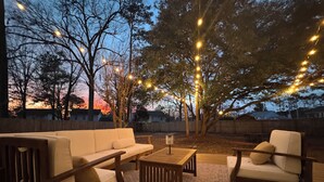 Eine Terrasse im Freien mit einer Couch, Sesseln und einem Couchtisch.