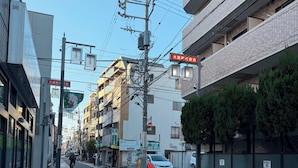 Una calle con edificios, cielo despejado y una flecha roja señalando a la derecha.
