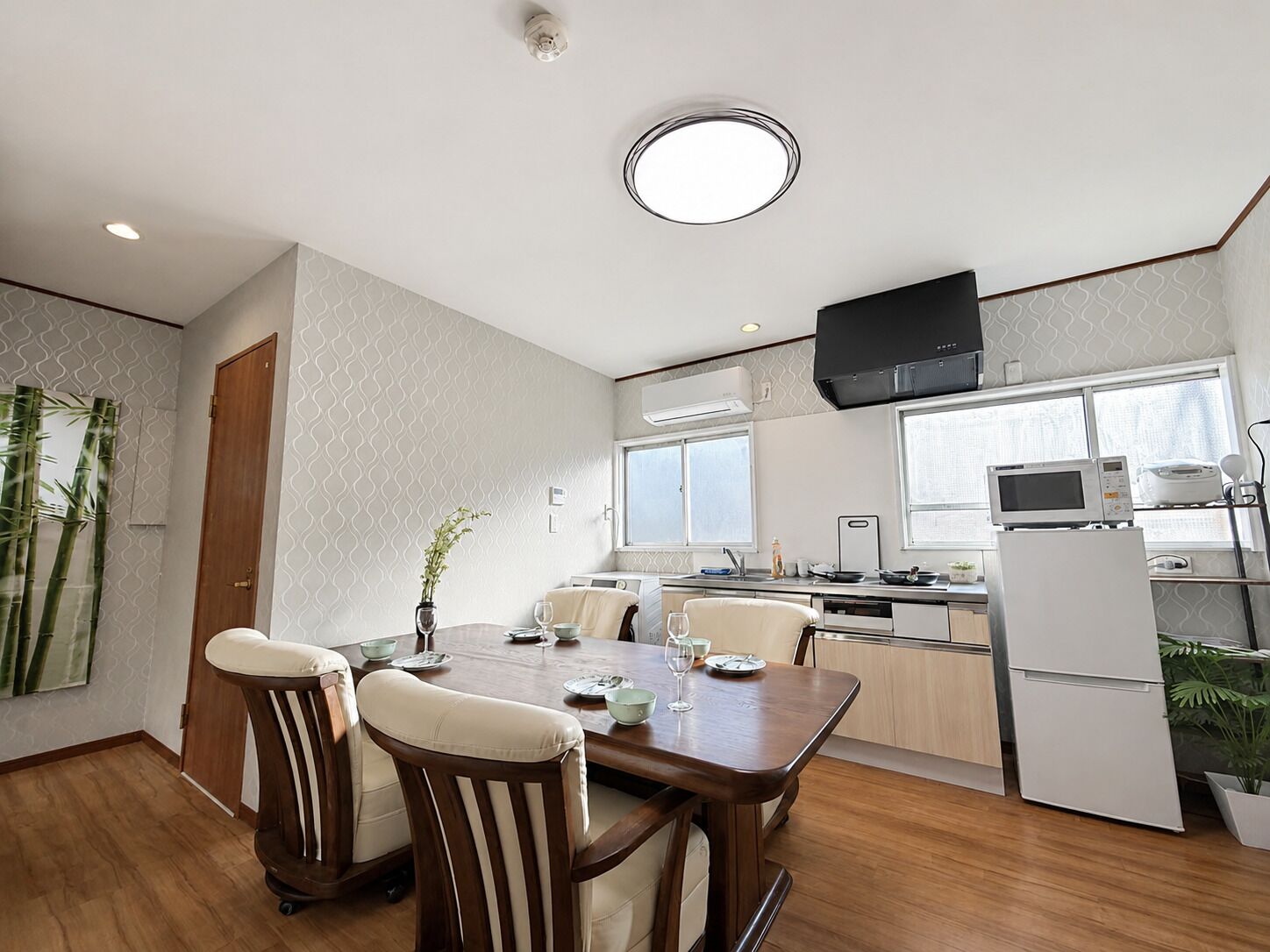 A modern kitchen with a dining area, wooden furniture, and a built-in microwave.