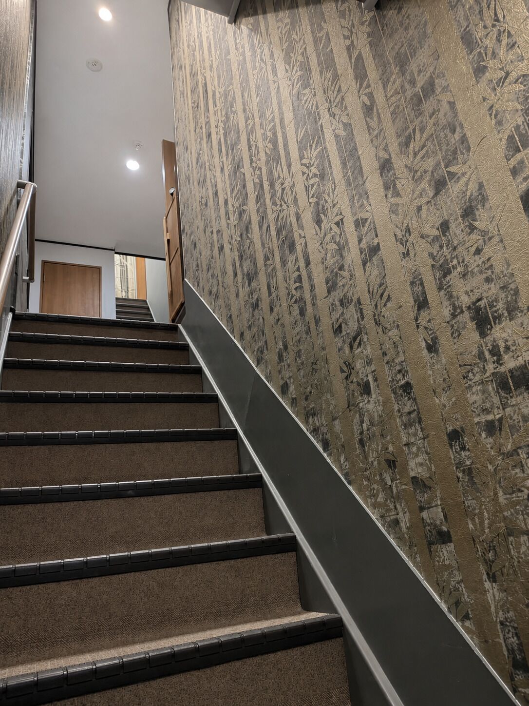 A staircase with a textured wall and a handrail.