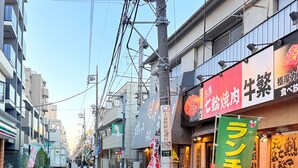 Vista de la calle con varias tiendas, incluyendo una 7-Eleven y un restaurante con un letrero verde.