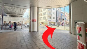 Un espacio interior amplio con suelo de baldosas, techo alto y vista a la calle.
