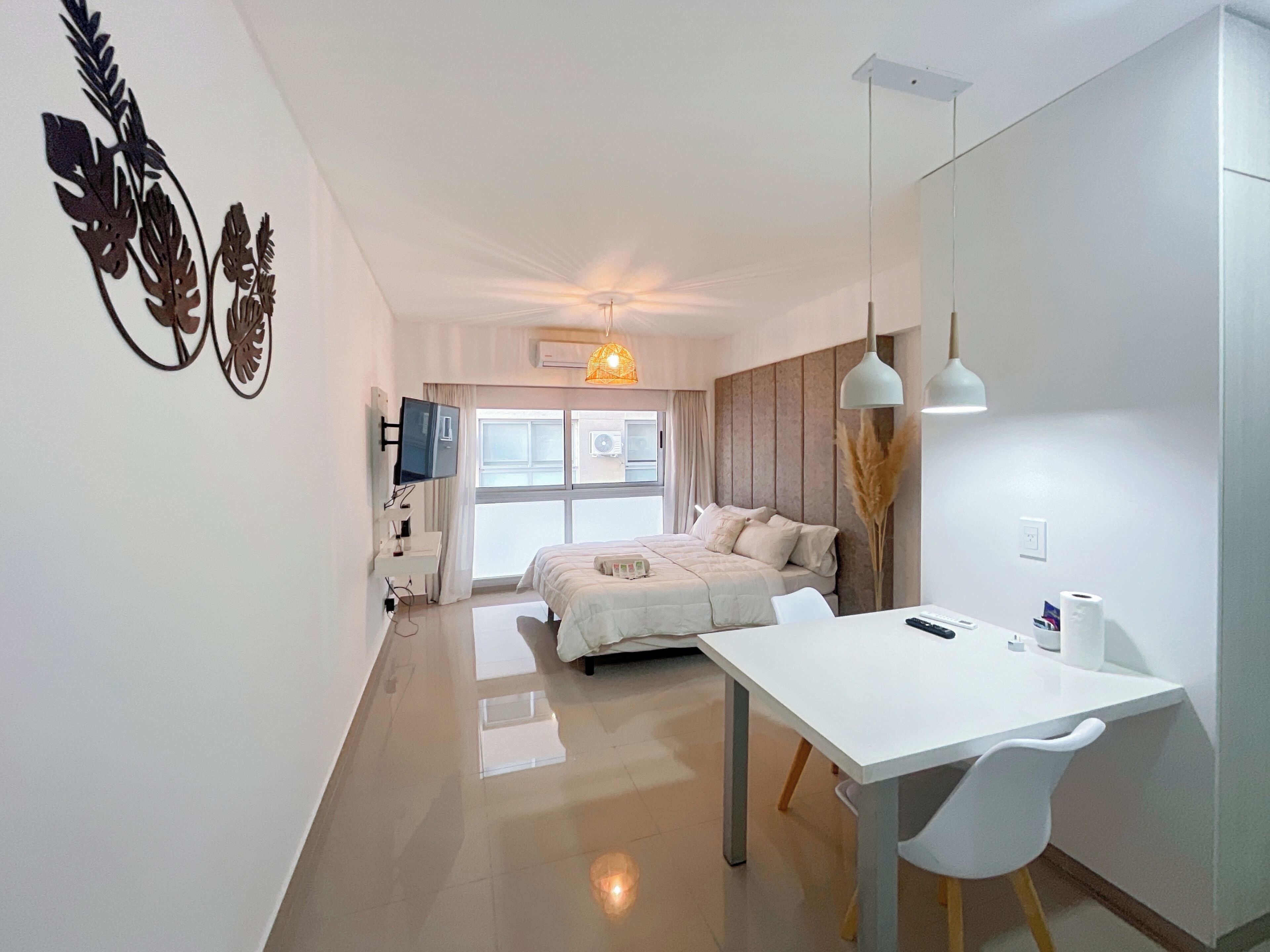 A modern hotel room with a bed, a desk, and a TV.