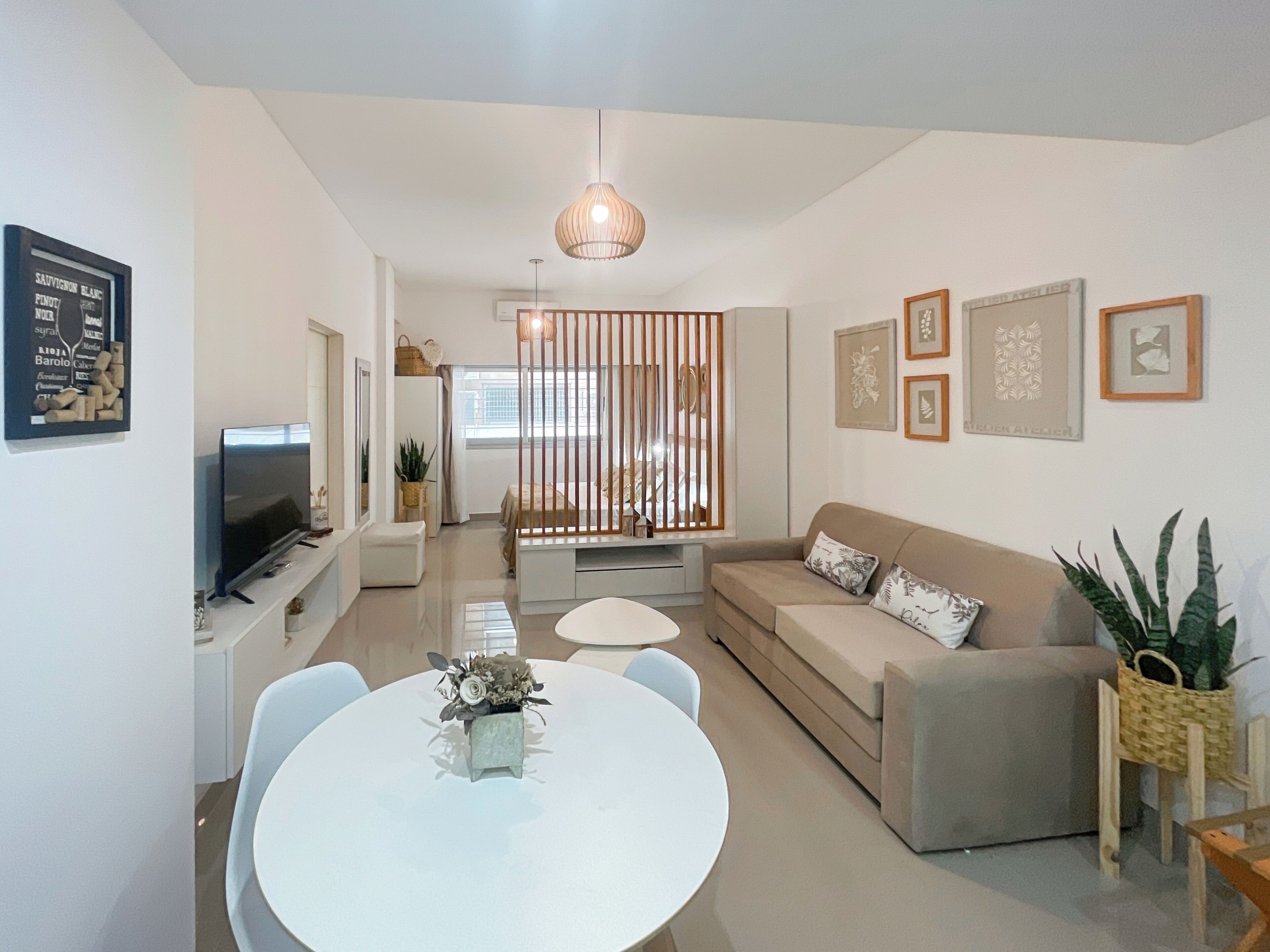 A modern living room with a sofa, a dining table with chairs, a TV, and decorative items.