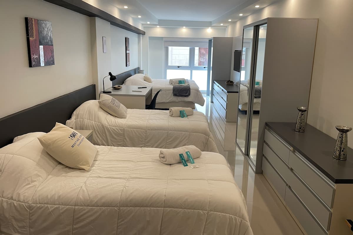 A hotel room with two beds, a desk, a dresser, and a large mirror.