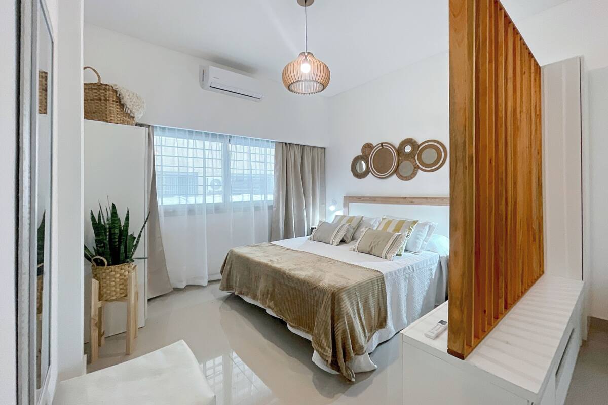 A modern bedroom with a bed, bedside table, and a large window.